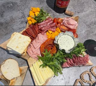 A board of cheeses,
        deli meats and dips